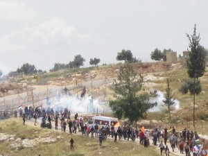 Masses of tear gas and shock grenades cover the demonstrators by the wall in Bi'lin.